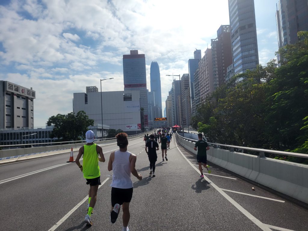 Picture of runners, taken from inside the pack during a race, while running along a skyline in a cityscape