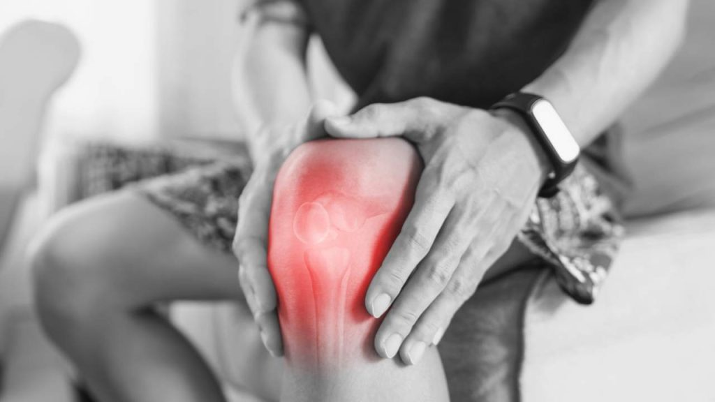 An runner grabbing his knee, highlighted in red to indicate runner's knee